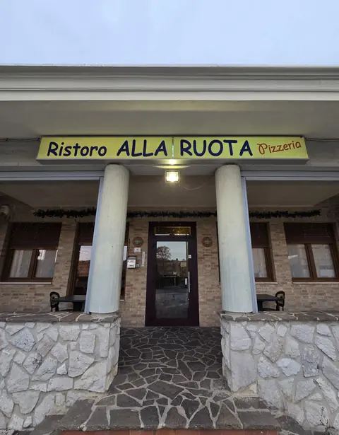 L'ingresso con l'insegna gialla Ristoro alla Ruota Pizzeria e le colonne bianche