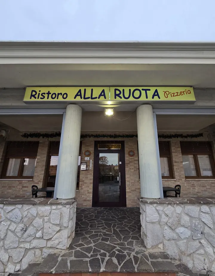 L'ingresso della pizzeria in via Pasubio 16, con l'insegna Ristoro alla Ruota Pizzeria e le colonne bianche