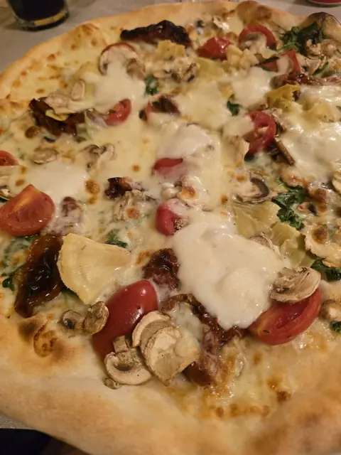 Pizza bianca con pomodorini, funghi, carciofi, pomodori secchi e rucola