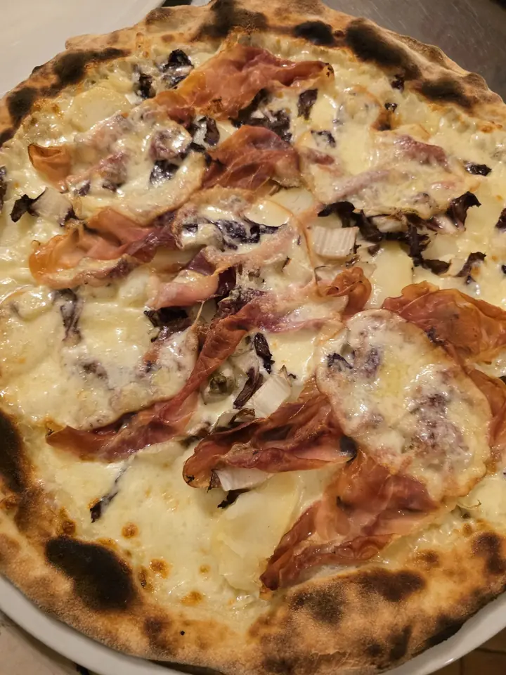 Pizza Inverno, bianca con radicchio, speck cotto in forno e provola fusa, appena uscita dal forno a legna