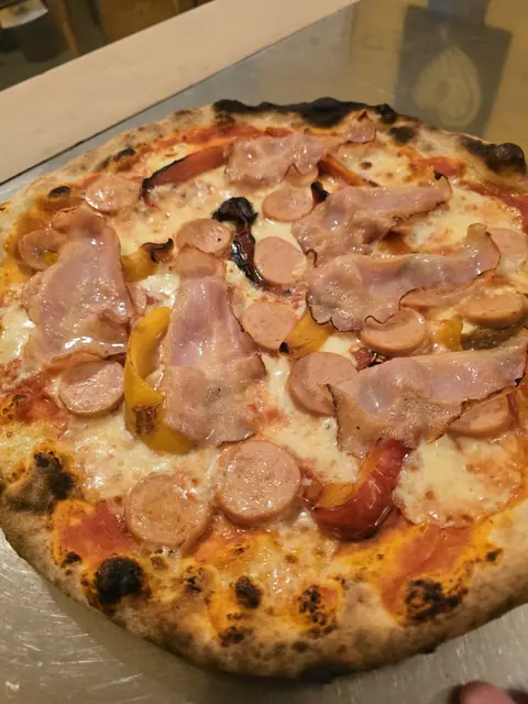 Pizza Stuzzicante con pancetta affumicata, würstel a rondelle e peperoni gialli e rossi