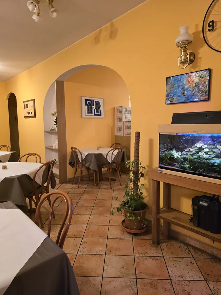 Un angolo della sala con l'acquario, i quadri e un tavolo per due sotto l'arco